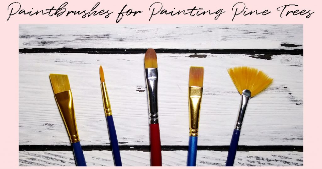 Five paintbrushes (an angle, round, filbert, flat, and fan) on a white-washed wooden background.