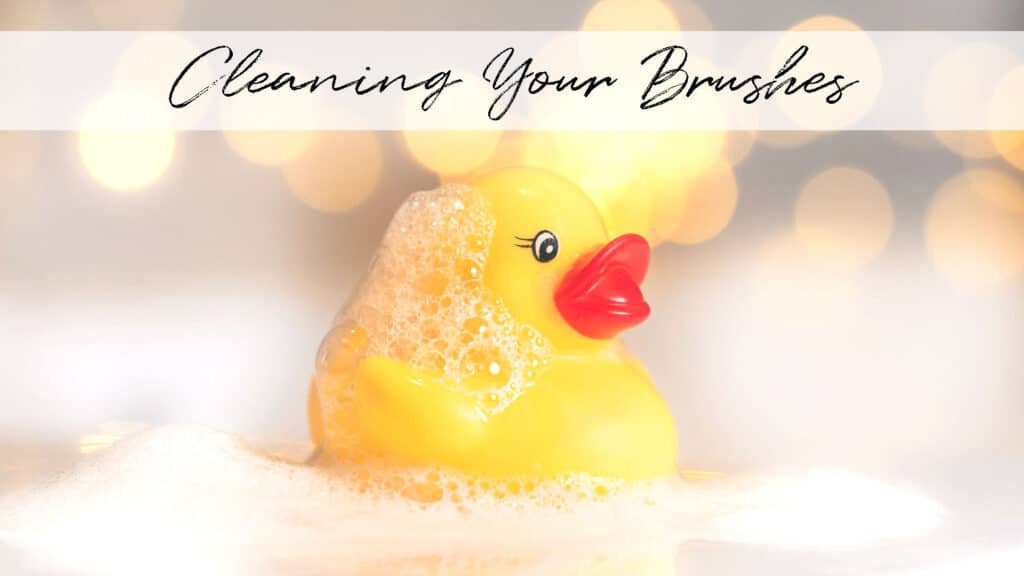 A little yellow rubber ducky covered in soap bubbles with the title "Cleaning your Brushes"