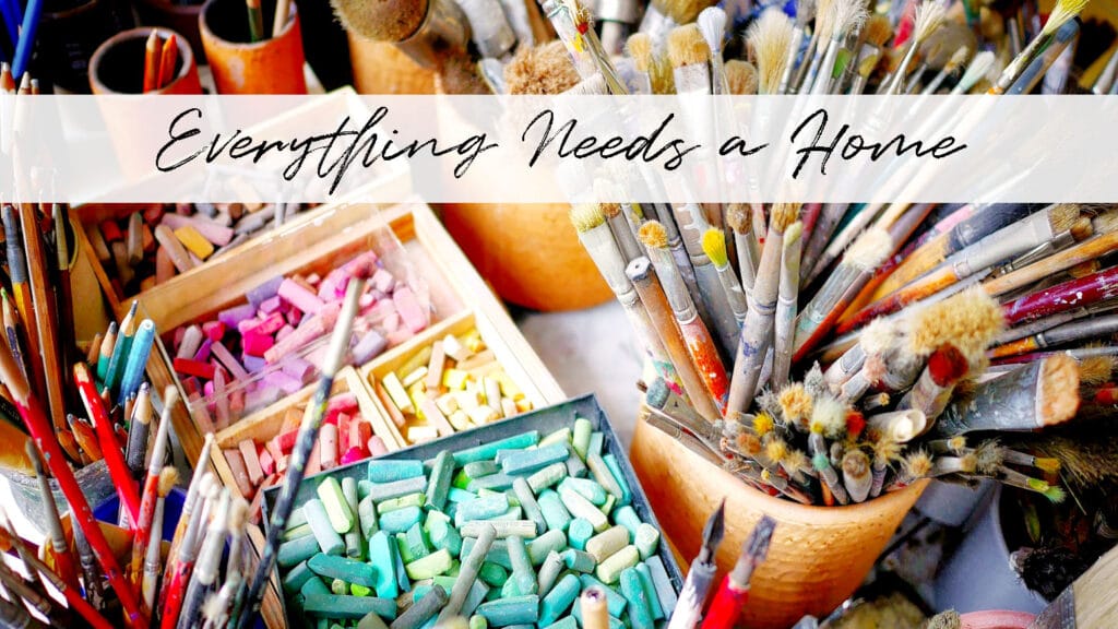 A jumbled mess of brightly colored chalk, paint brushes, and other assorted art and craft supplies with the title "Everything Needs a Home"