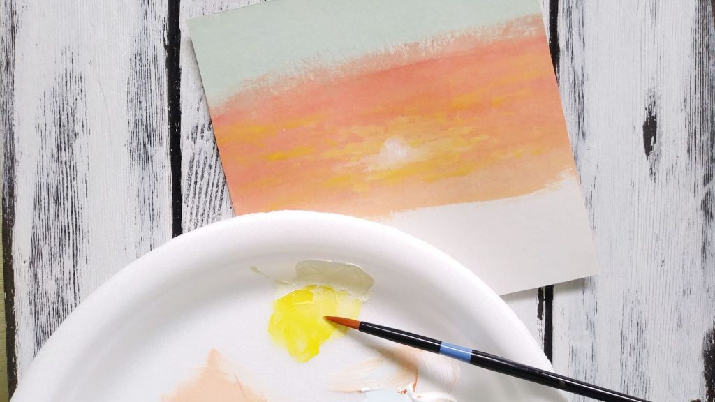 Step three showing a closeup of yellow paint on a palette and illustrating how I added the sun to my painting.
