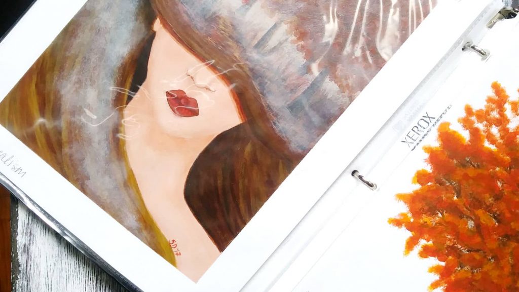 An open 3-ring binder that is used as a portfolio for acrylic paintings done on paper.