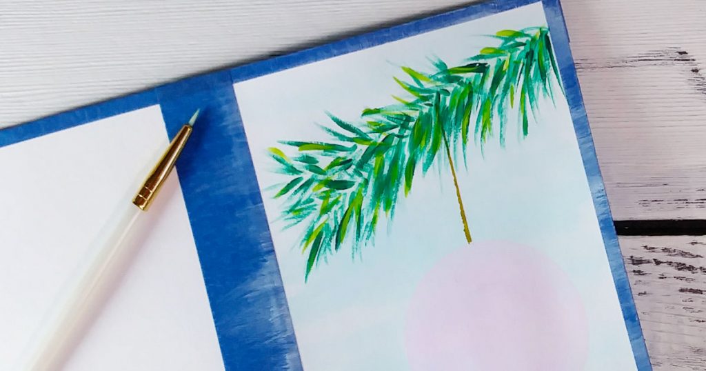 A close-up of how we can make a holiday card with acrylic paint that has a dark green fir branch with lovely lime green highlights