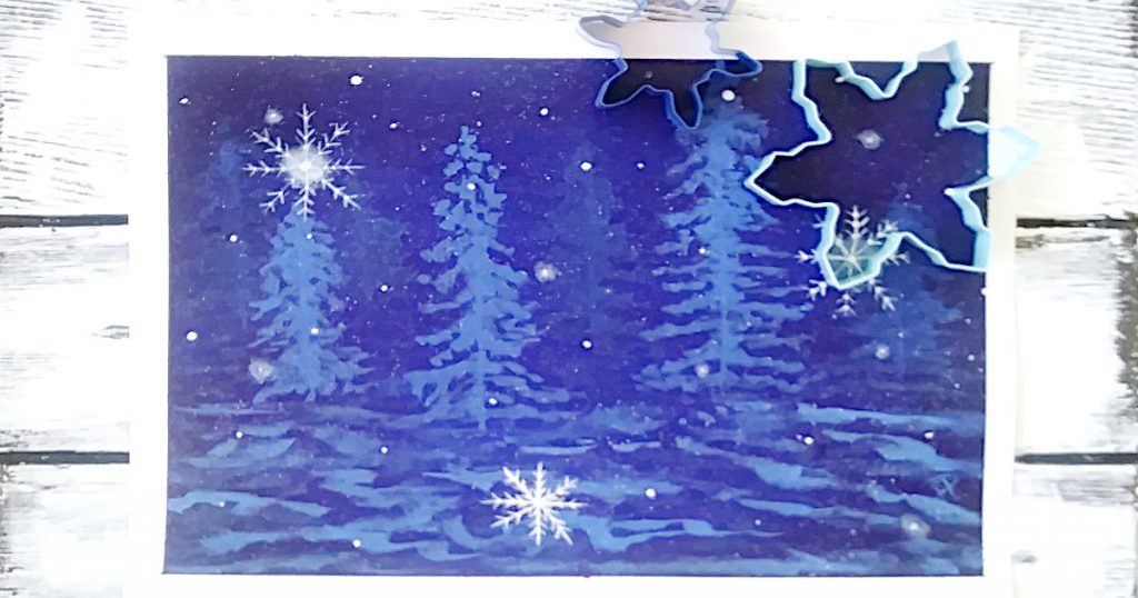 Snowflake shaped cookie cutters used as a template to paint snowflakes on the dark blue nighttime winter landscape