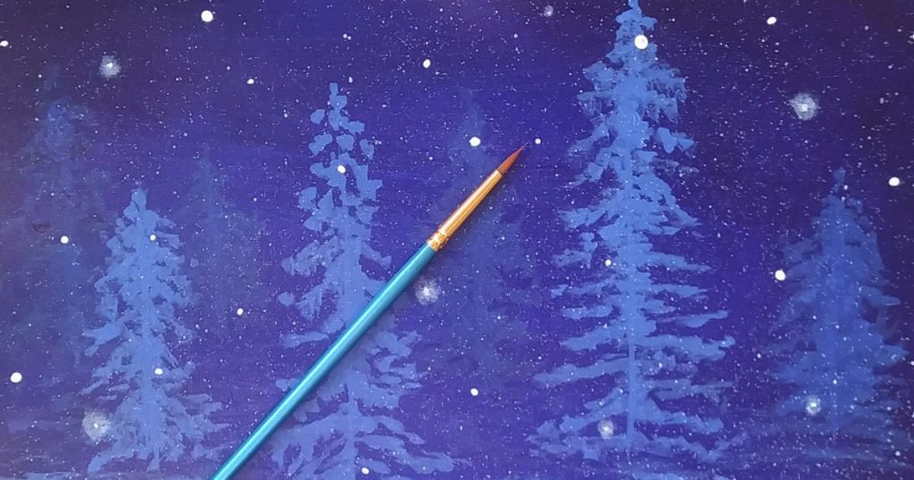 Using the end of the paintbrush handle to create dot snowflakes to add to the wintry landscape painting