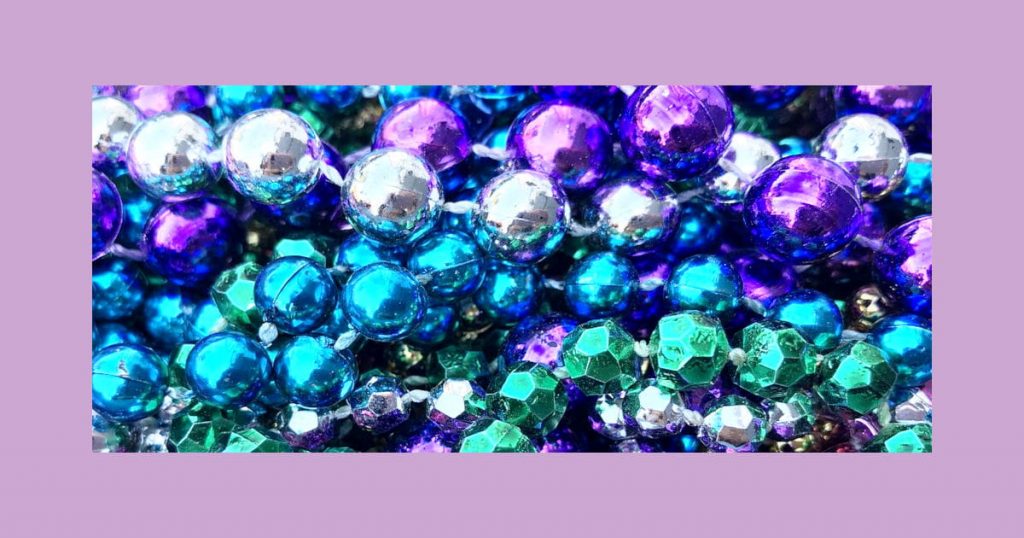 A pile of purple, silver, and green beads which fits perfectly in our list of great Fat Tuesday easy painting ideas