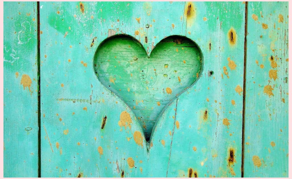 A turquoise painted wooden fence with a heart cutout that's an example of the principle of variety using shape to create visual interest.