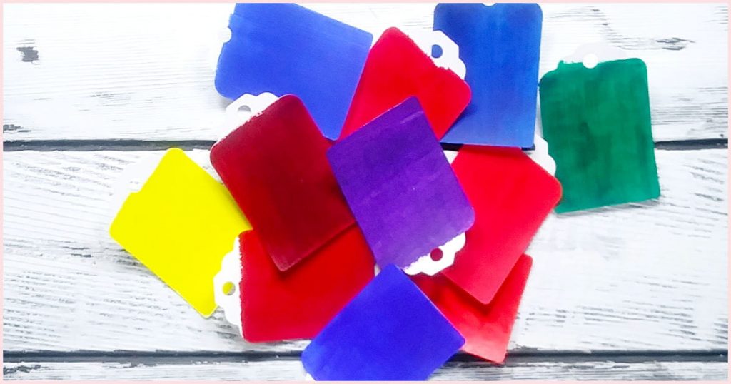 A pile of paper paint chips in blues, reds, yellow, green, and purple. These are the colors used in the quest to figure out how to make magenta paint.