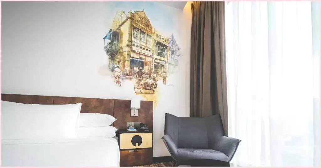 A hotel room with a mural painted above the headboard. Can you use acrylic paint on walls? Sure but placement is crucial so consider where your painting will be and how much traffic the area gets.
