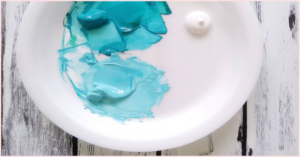 A white palette with two different shades of turquoise paint on it and some white paint off to the side.