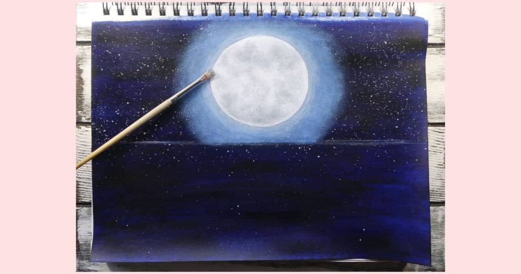 The same scruffy brush laying on top of the moon painting. This time the brush is covered in light grey paint, which is used to soften the edges of the mid-tone grey craters.