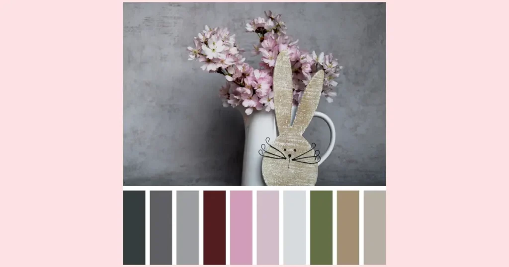 A wooden white-washed rabbit cutout leaning against a pale blue water pitcher that's filled with cherry blossom branches. Underneath is a row of paint chips to demonstrates some of the colors in the image.