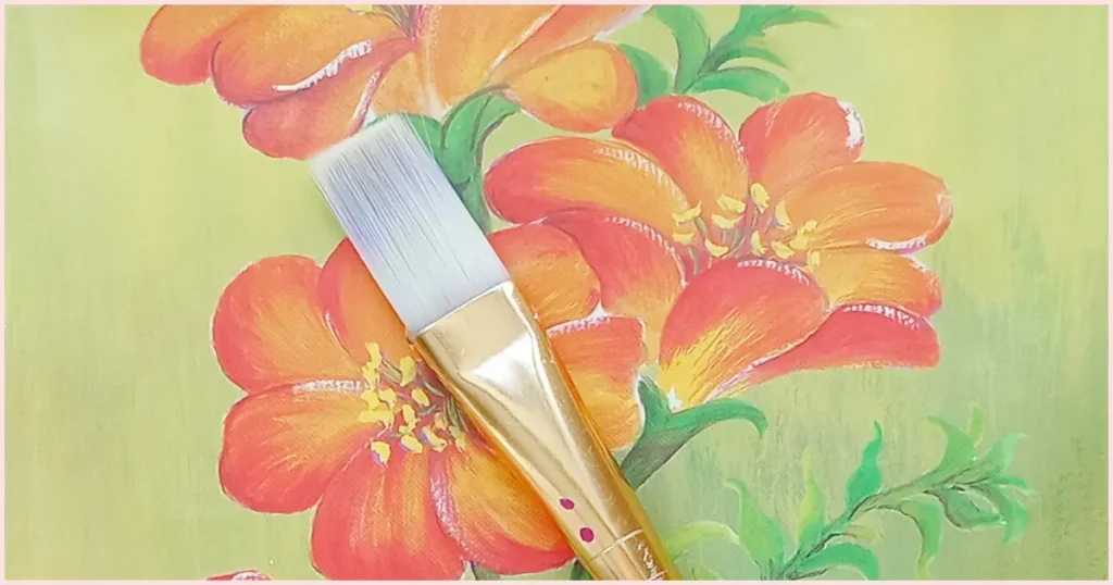 A white bristle flat paint brush on an orange floral background.