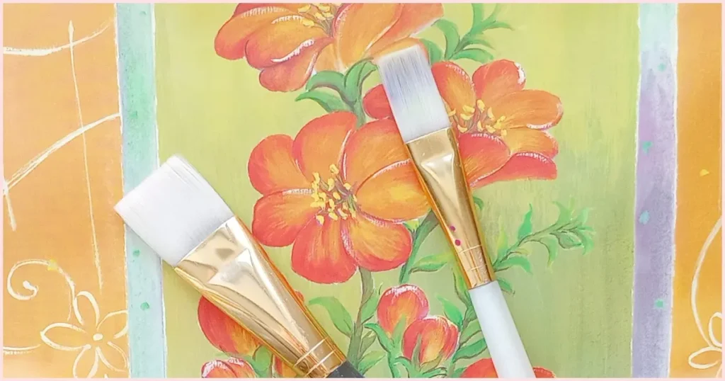 A flat brush and a bright brush together on an orange floral background.