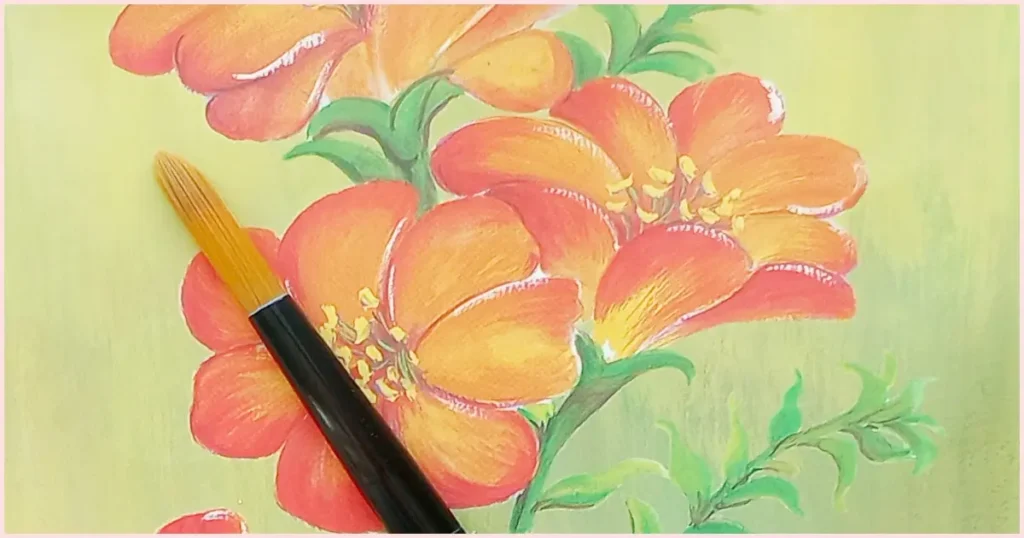 A round paint brush on a green background with orange flowers