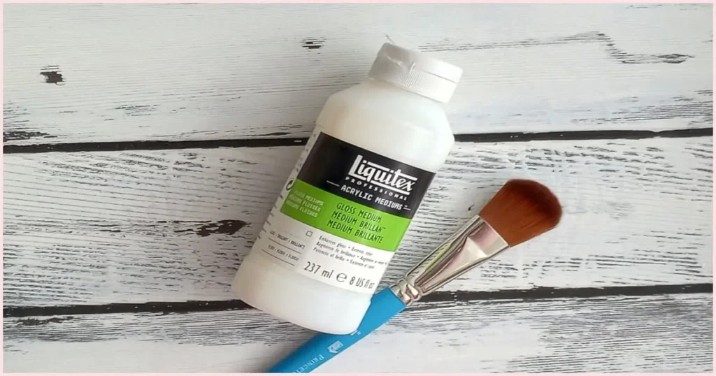 A bottle of Gloss acrylic medium and a mop paintbrush with a blue handle