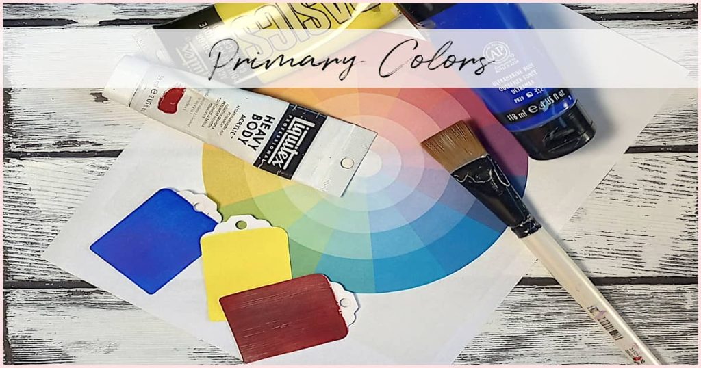 A paper color wheel, paint tube, paint brush, and three paint chips of red, blue, and yellow to show the primary colors.