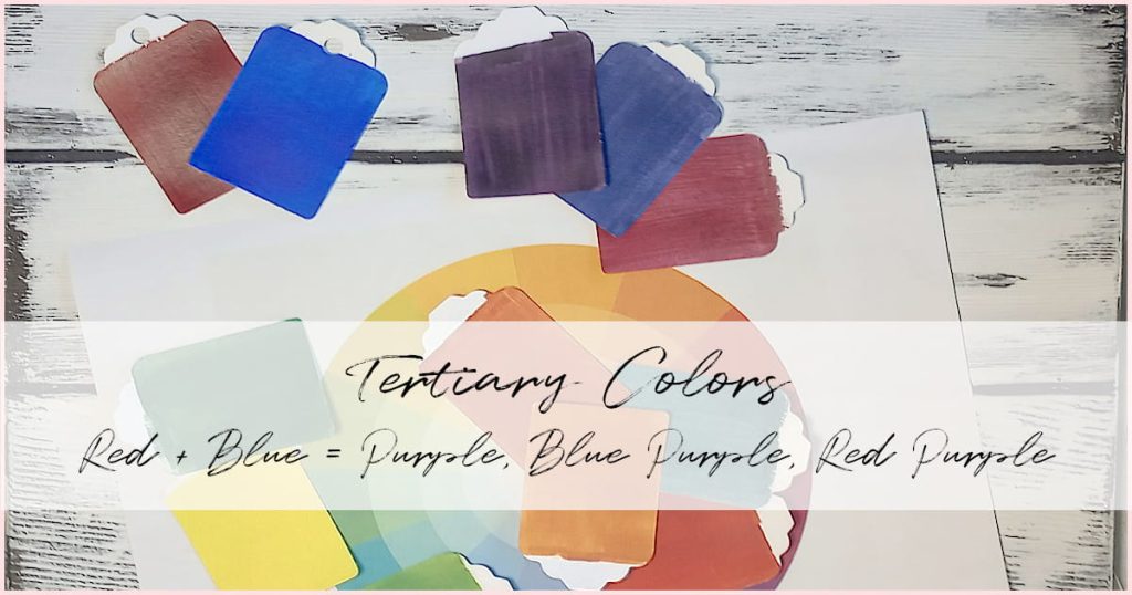 Assorted tones of purple paint chips next to a red and blue paint chip on a white wood background with various other paint chips scattered on top of a color wheel.